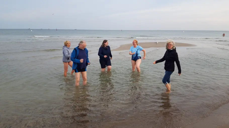Eine Gruppe von 5 Menschen beim Wassertreten am Warnemünder Strand